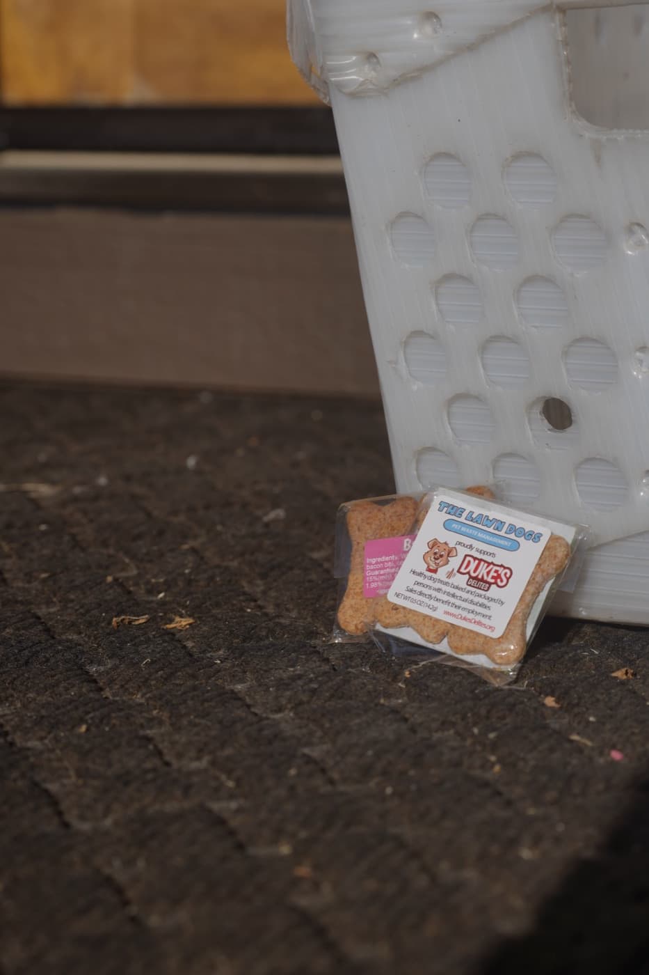 A Lawn Dogs branded Duke's Delites dog treat left on a doormat at a client's front door